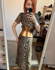 Aria Margo Eclipse gold leather corset belt worn over a leopard print dress in a mirror selfie