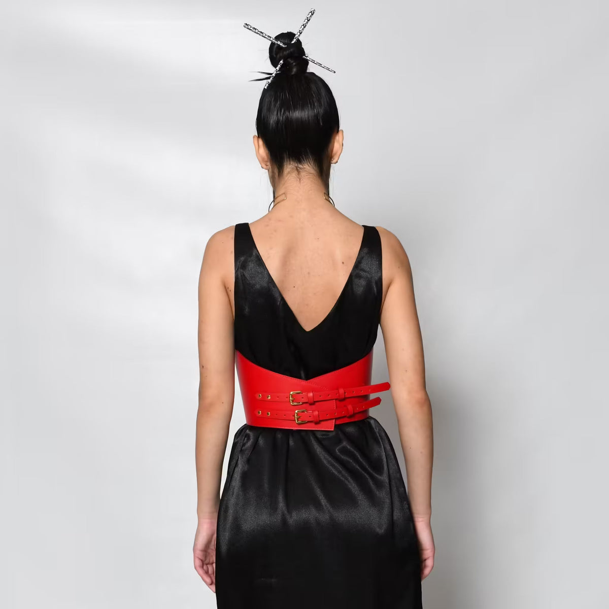 Aria Margo red Italian leather under-bust belt with double buckles worn over a black dress, back view.
