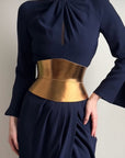 Aria Margo gold metallic Italian leather corset belt with an hourglass silhouette worn over a navy blue dress.