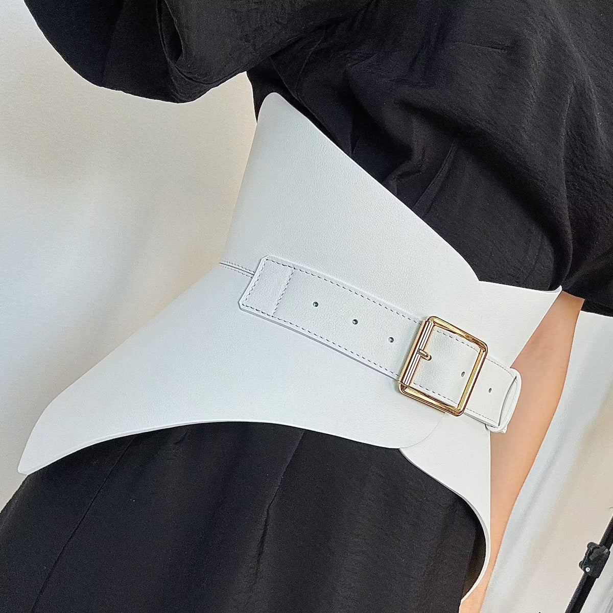 Aria Margo white Italian leather corset belt with a gold buckle worn over a black outfit to define the waist.