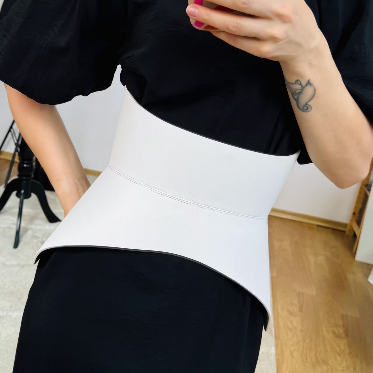 Aria Margo white Italian leather corset belt worn over a black dress to accentuate the waist and hips.