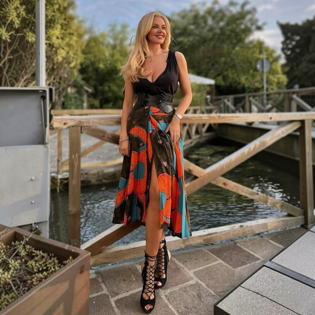 Aria Margo black croc-embossed leather corset belt worn over a colourful patterned midi dress outdoors
