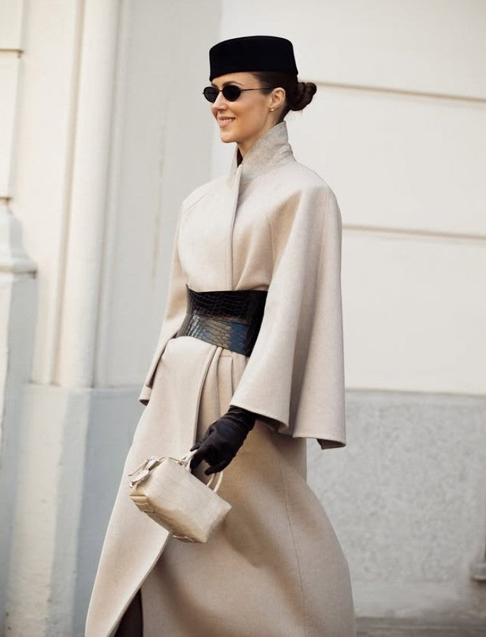 Aria Margo black croc-embossed leather hourglass corset belt worn over a beige wool coat by a stylish woman.