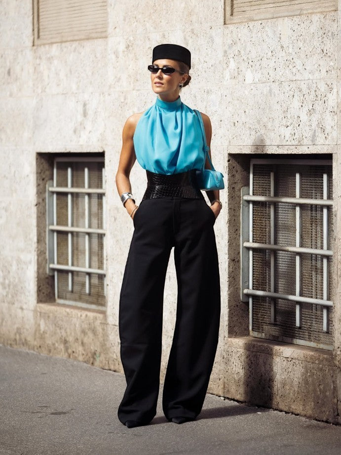 Aria Margo black croc-embossed leather hourglass corset belt worn over wide-leg trousers and a blue halter top.