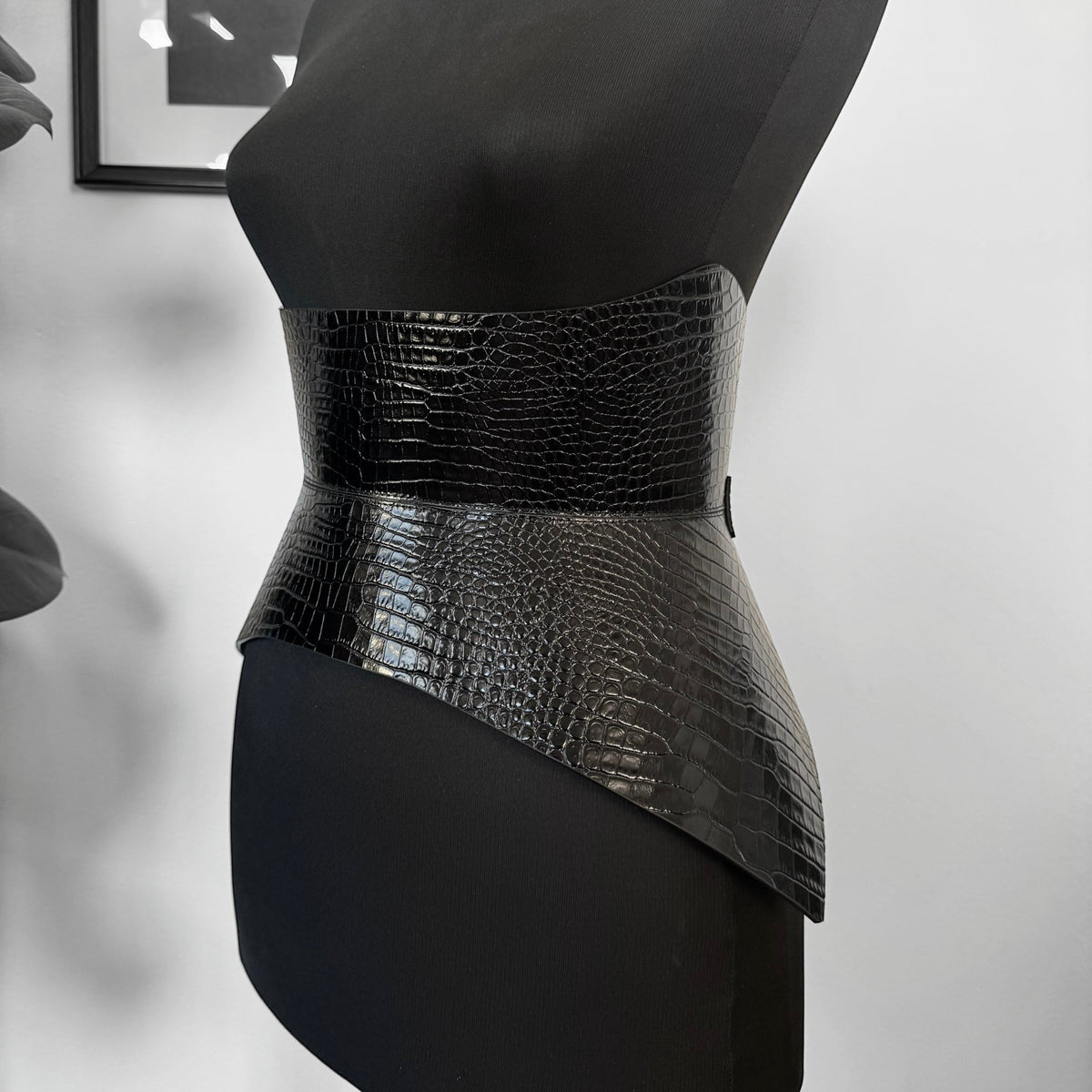 Aria Margo black croc-embossed Italian leather corset belt with a shaped waist and hip design on a mannequin.