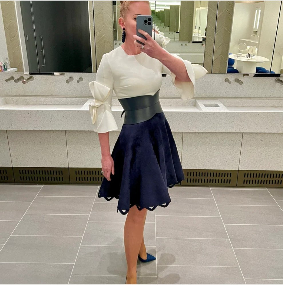 Aria Margo black leather hourglass corset belt worn over a white top and navy skirt in a mirror selfie
