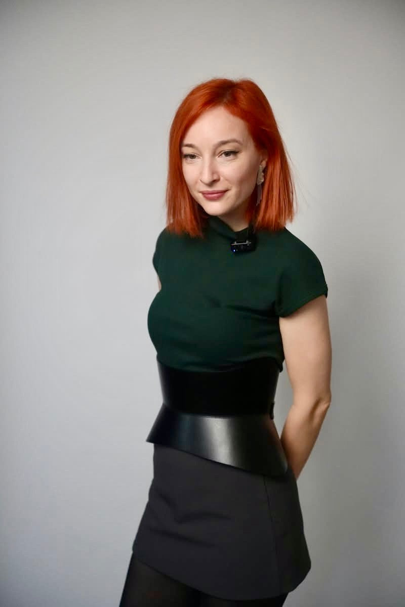 Aria Margo black Italian leather corset belt worn over a dark green top, creating a defined hourglass silhouette.