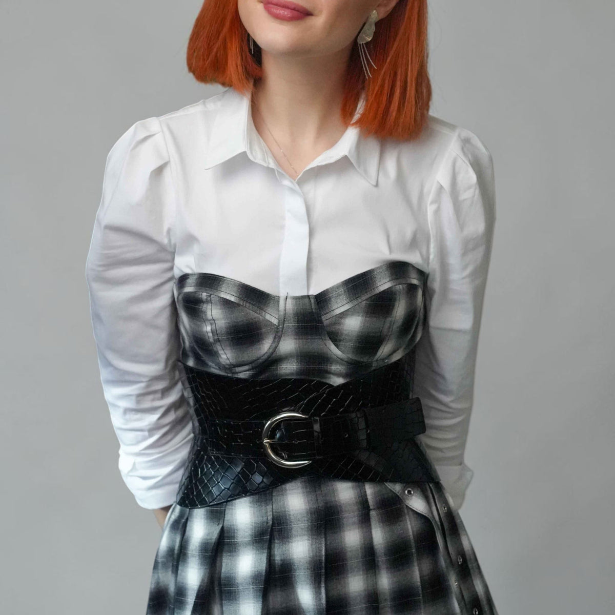 Aria Margo black croc-embossed leather hourglass corset belt worn over a white shirt and plaid dress