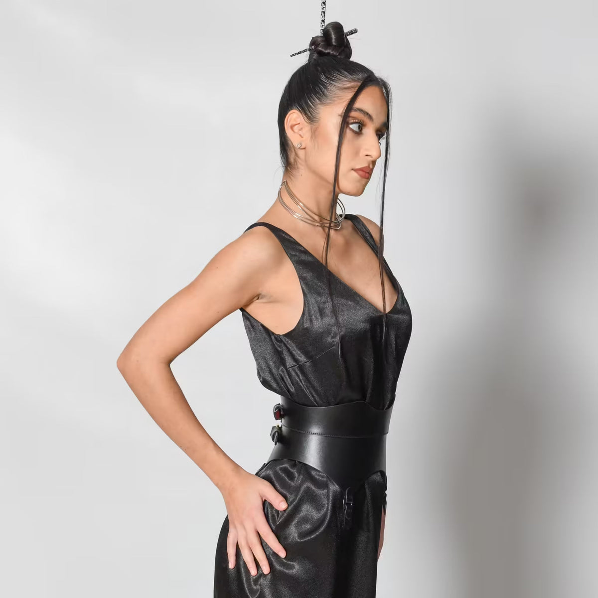 Aria Margo black leather corset belt with gold buckles worn by a model over a black satin dress