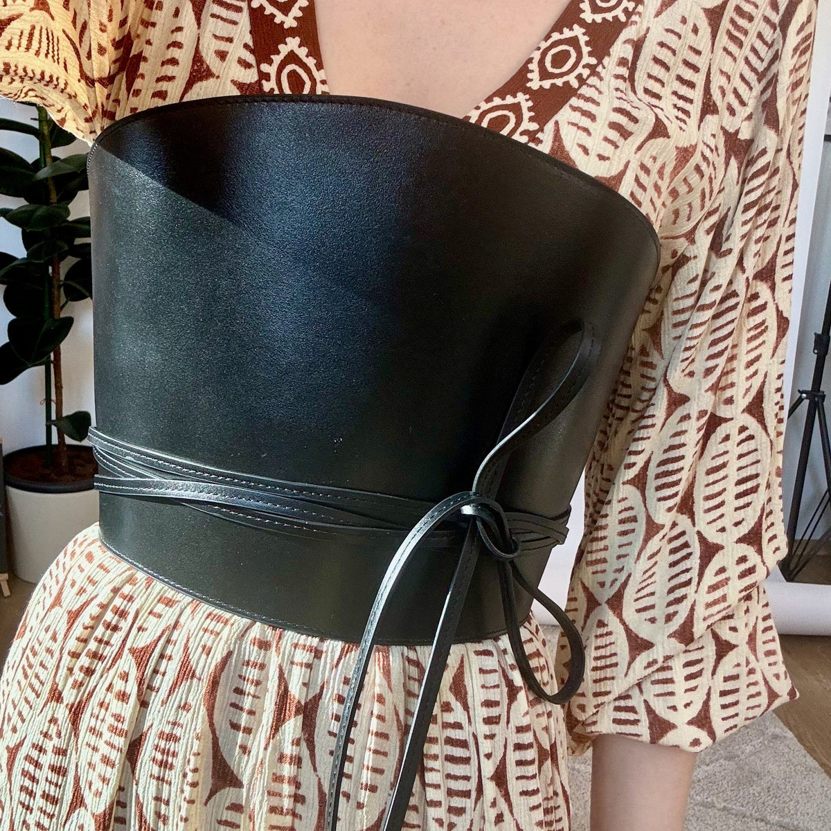 Aria Margo black Italian leather corset belt with wrap-around cord detail worn over a patterned dress