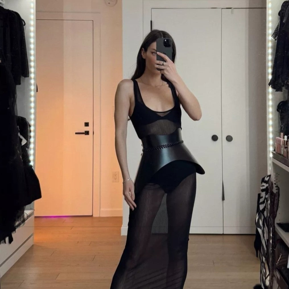 Aria Margo black leather Nova corset belt worn over a sheer black dress to create a sculpted hourglass silhouette.