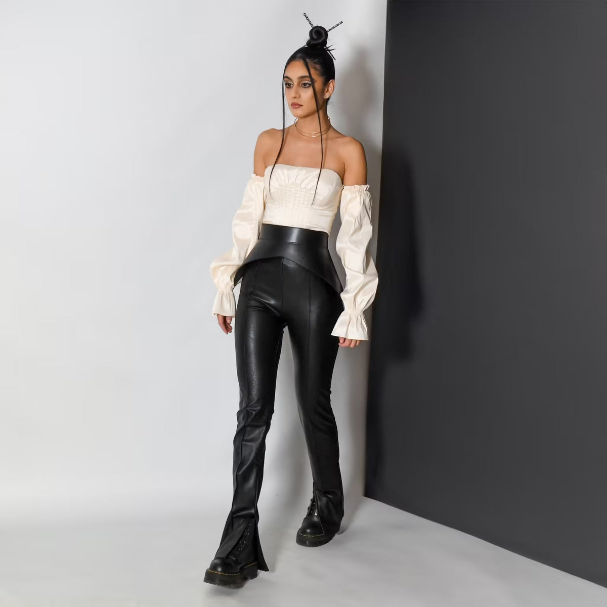 Aria Margo black leather peplum corset belt worn over a white off-shoulder top and black trousers