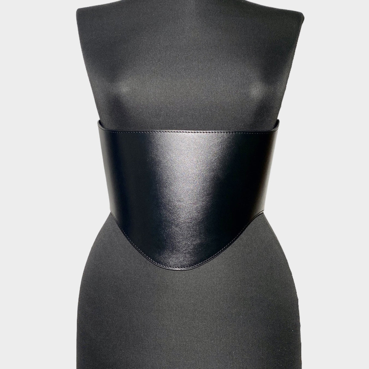Aria Margo black Italian leather under-bust belt with a curved design on a mannequin torso.