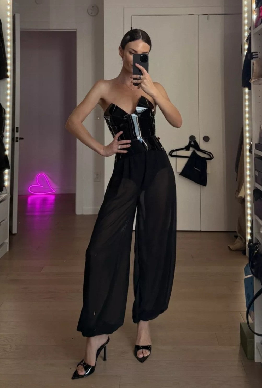 Aria Margo black patent leather corset belt worn over sheer trousers for a structured feminine silhouette.
