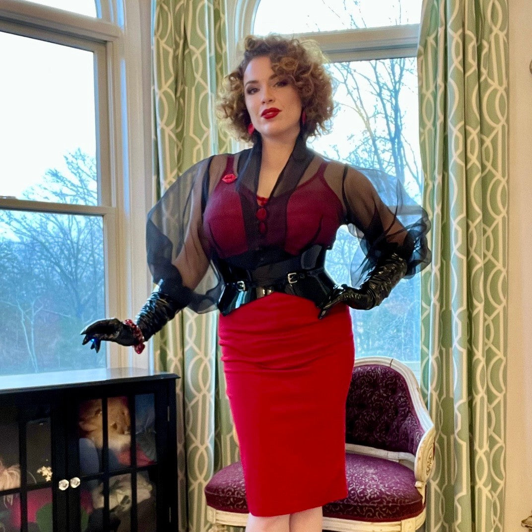 Aria Margo black patent leather Thorns corset belt worn by a woman in a red dress and sheer black blouse