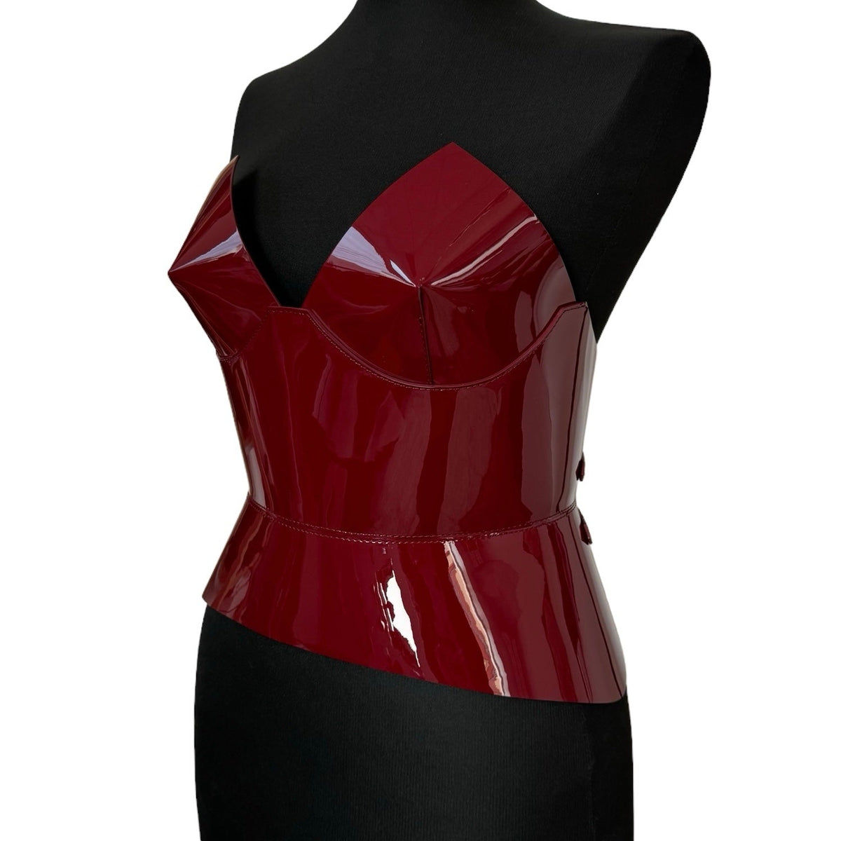 Aria Margo burgundy patent leather corset with a structured, high-shine finish on a black mannequin torso.