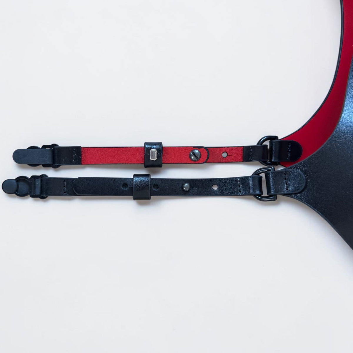 Aria Margo black and red leather corset belt with adjustable suspender straps and metal clips on a wooden surface