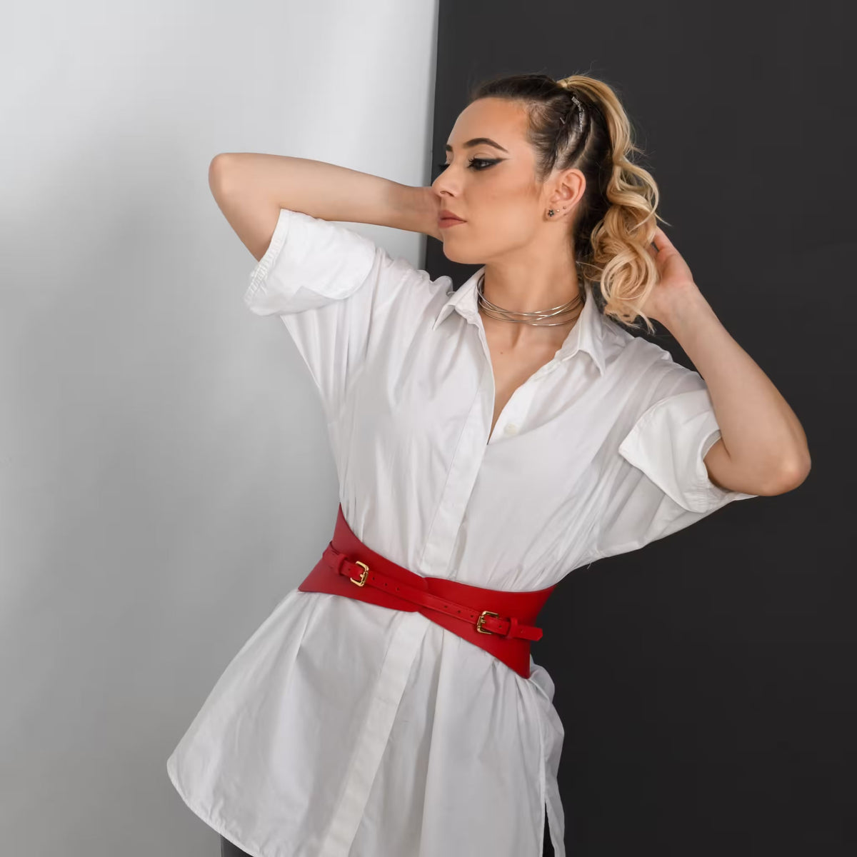 Aria Margo slim red Italian leather corset belt worn over a white button-down shirt for a defined waist shape.
