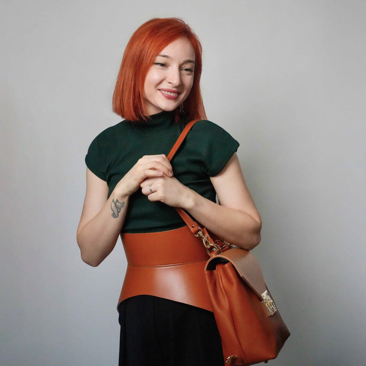Aria Margo Test brown leather corset belt worn over a dark green top, highlighting a feminine waist silhouette.
