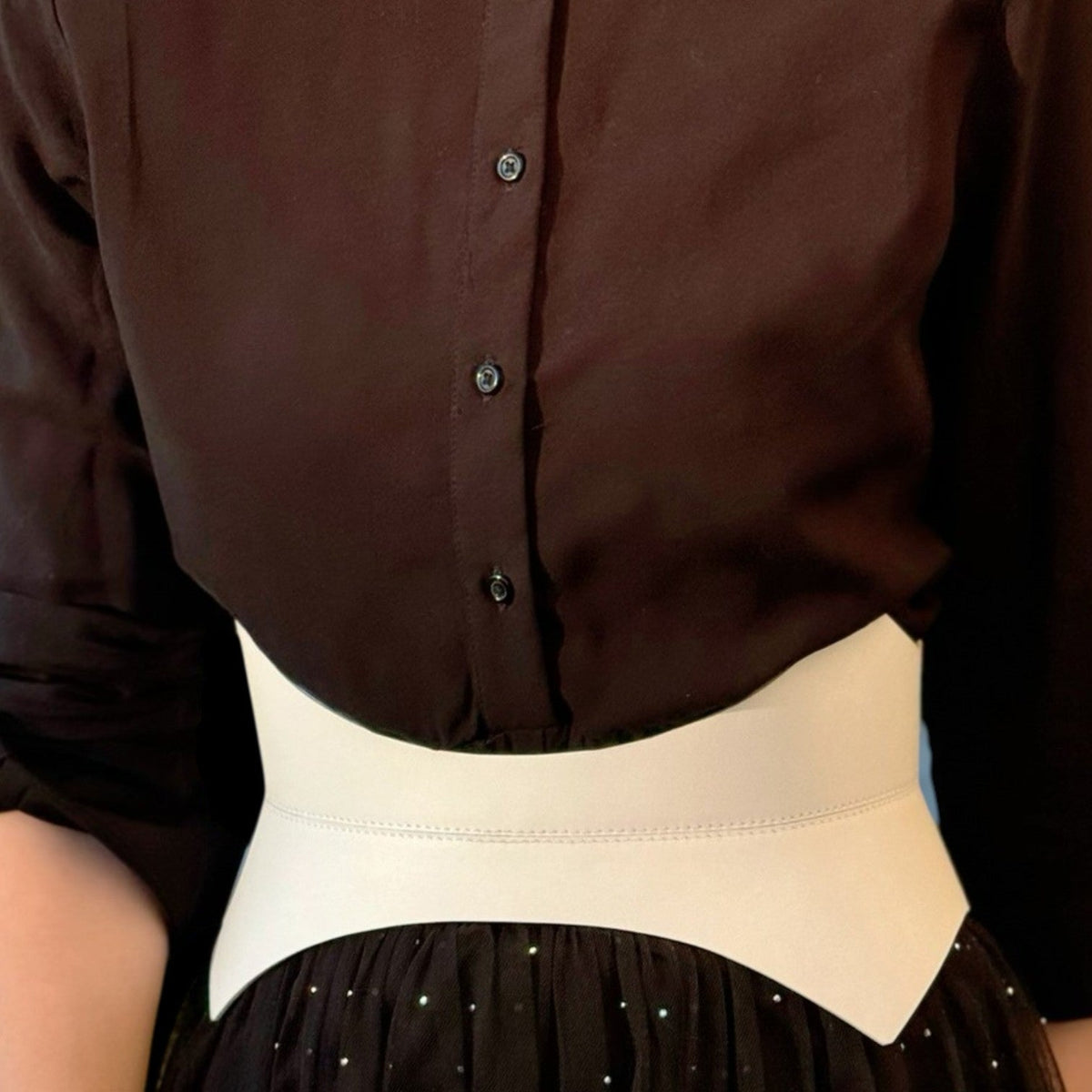 Aria Margo white Italian leather corset belt worn over a black button-down shirt and skirt