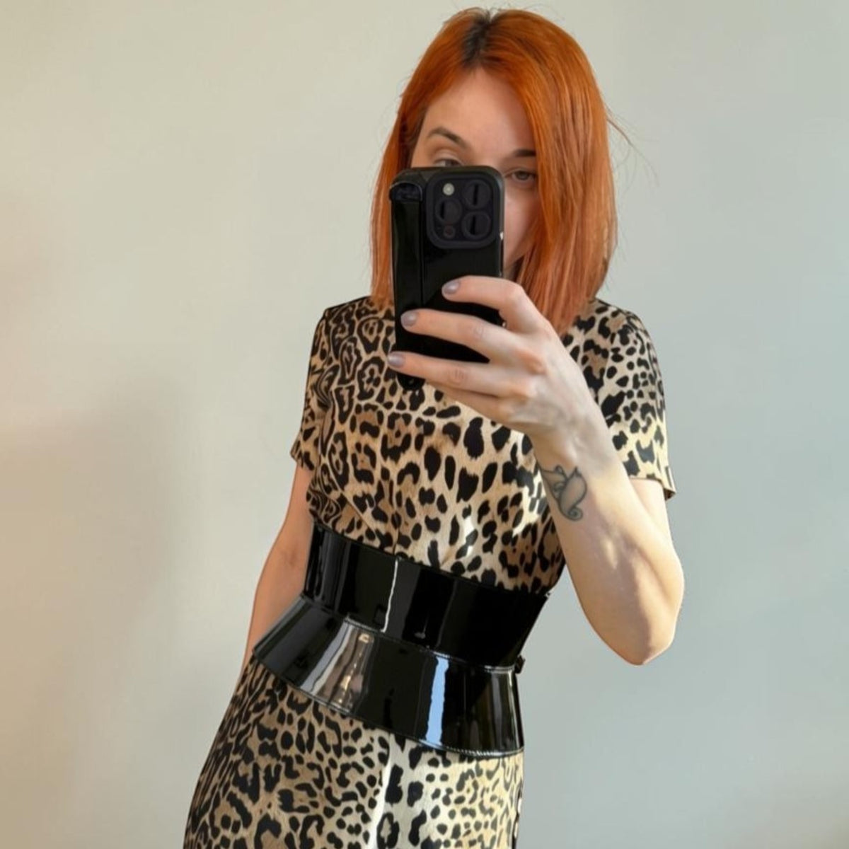 Aria Margo wide black patent leather corset belt worn over a leopard print dress for a defined hourglass shape
